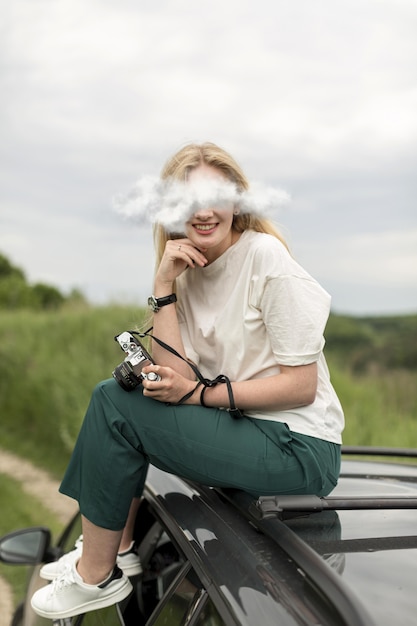 Free photo full shot smiley woman sitting on car