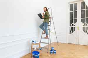 Free photo full shot smiley woman standing on ladder