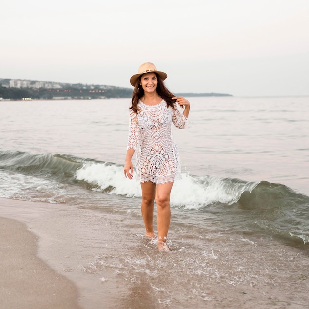 Donna piena di smiley del colpo che cammina sulla spiaggia