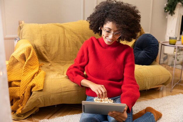 Full shot smiley woman watching movie on tablet