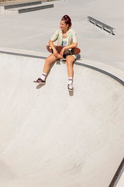 Полный снимок смайлик женщина со скейтбордом снаружи