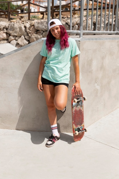 Foto gratuita donna sorridente a tutto campo con lo skateboard