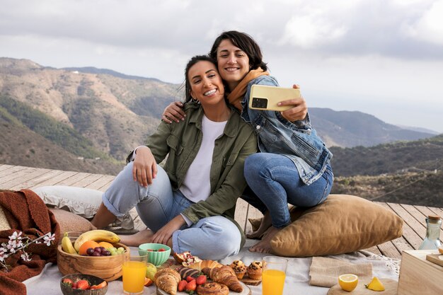 Full shot smiley women taking selfie outdoors