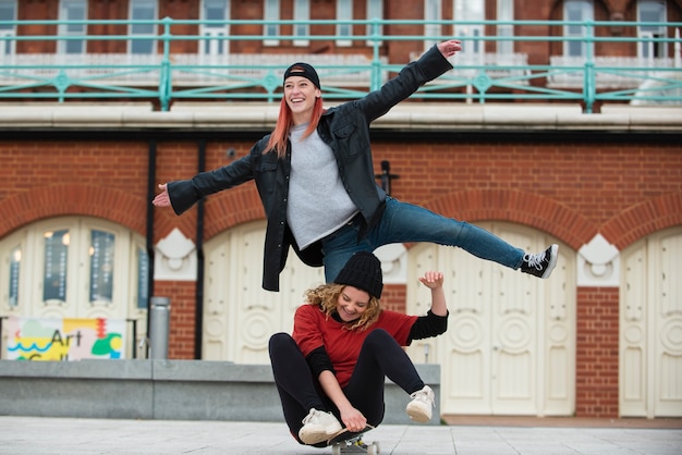 Free photo full shot smiley women with skateboard