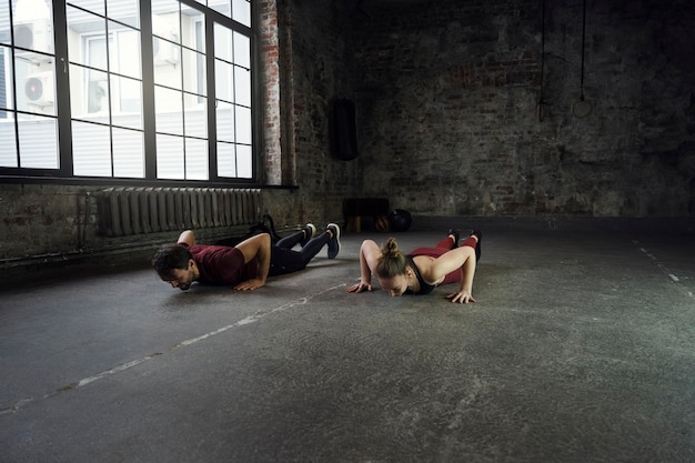 Full shot sports people doing burpees indoors