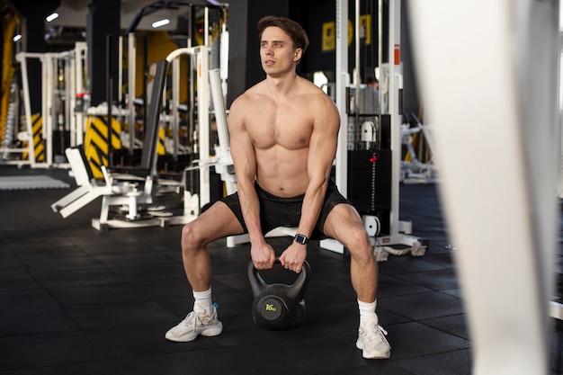 Free photo full shot sporty man training with kettlebell