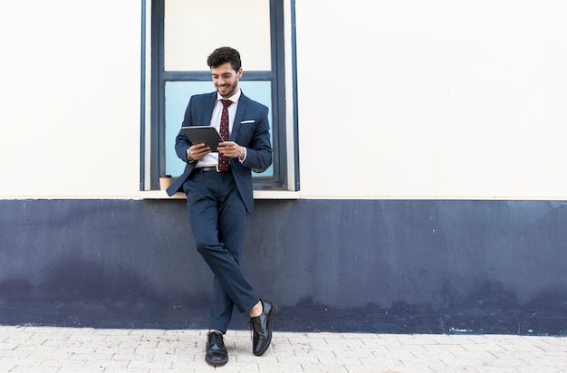 Uomo diritto della foto a figura intera con la sua compressa