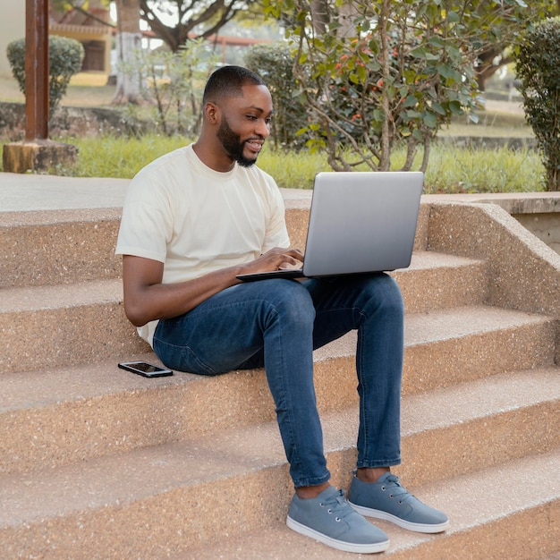 full shot student on stairs with laptop