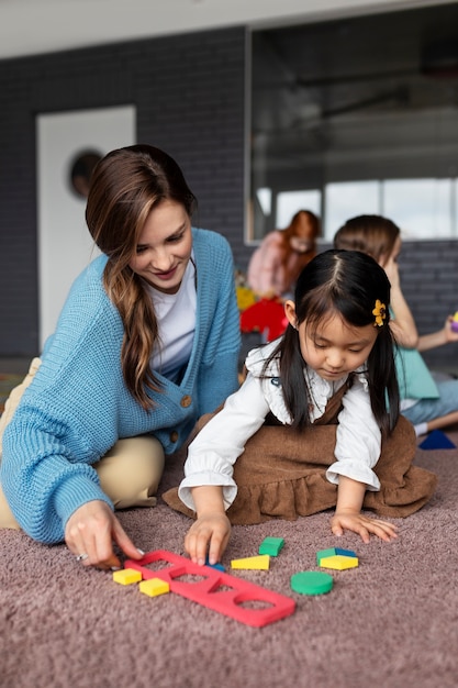 Full shot teacher helping girl learn