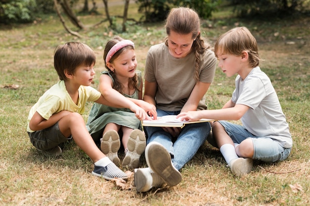 Full shot teacher and kids holding book