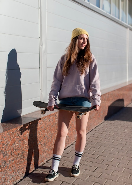 Full shot teen girl holding skateboard