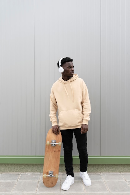 Full shot teen holding skateboard