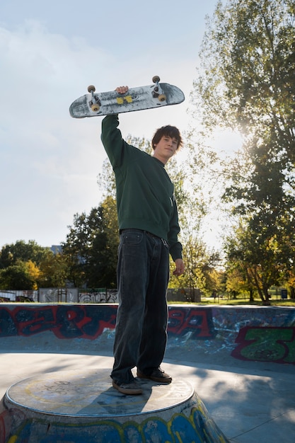 Бесплатное фото Полный выстрел подросток, держащий скейтборд