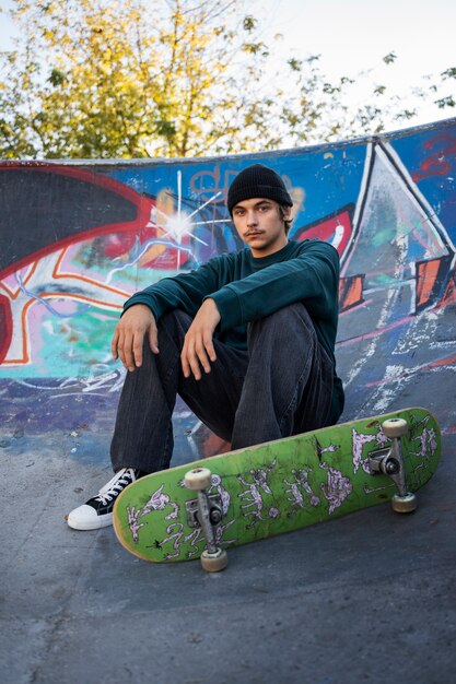 Full shot teen sitting with skateboard