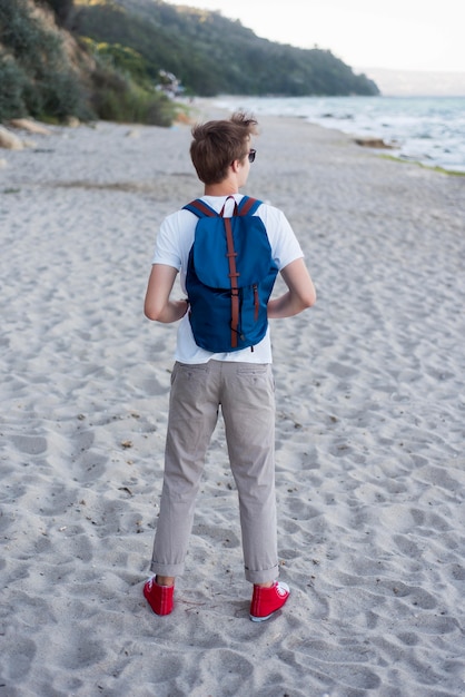 Foto gratuita teenager pieno del colpo con lo zaino sulla spiaggia
