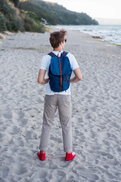 Teenager pieno del colpo con lo zaino sulla spiaggia