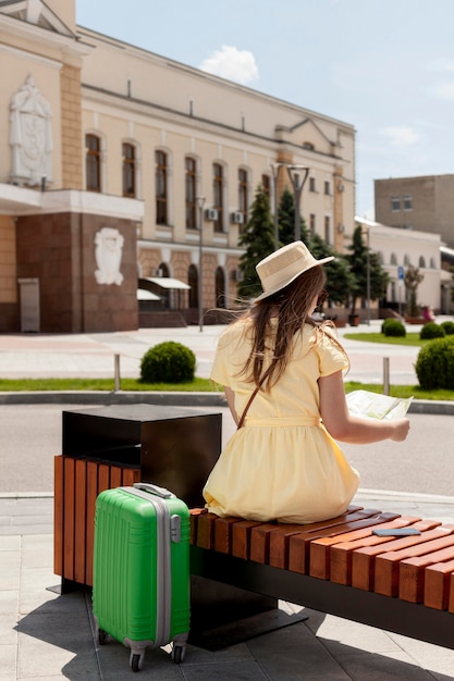 Foto gratuita turista della foto a figura intera che si siede sul banco