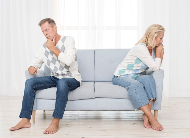 Full shot upset couple sitting on the couch