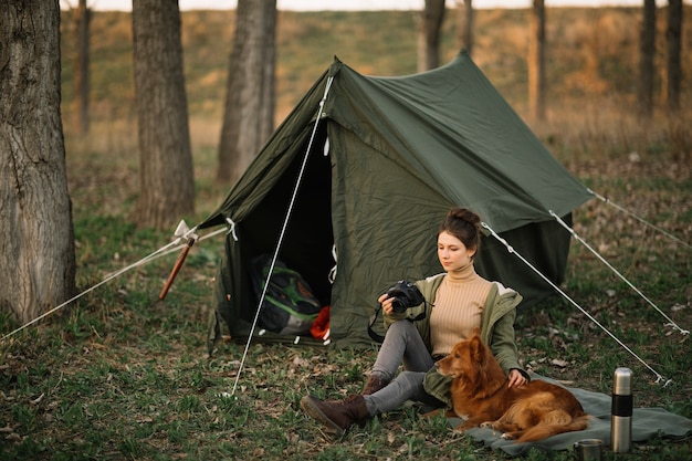 Бесплатное фото Полный выстрел женщина и собака возле палатки
