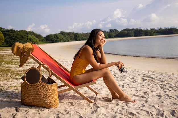 Полный снимок женщины на пляже с камерой