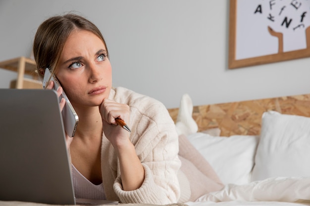 Donna piena del colpo a letto con il computer portatile