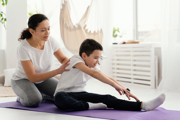 Full shot woman and boy on yoga mat