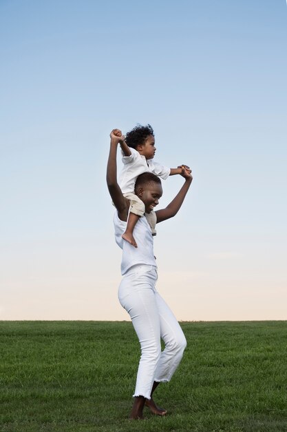 Full shot woman carrying kid on shoulders