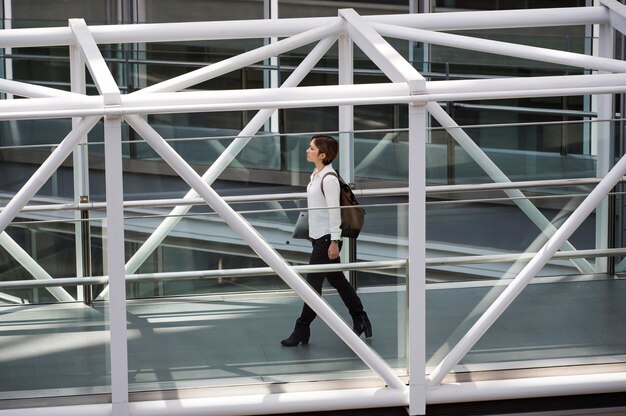 Full shot woman carrying laptop and backpack