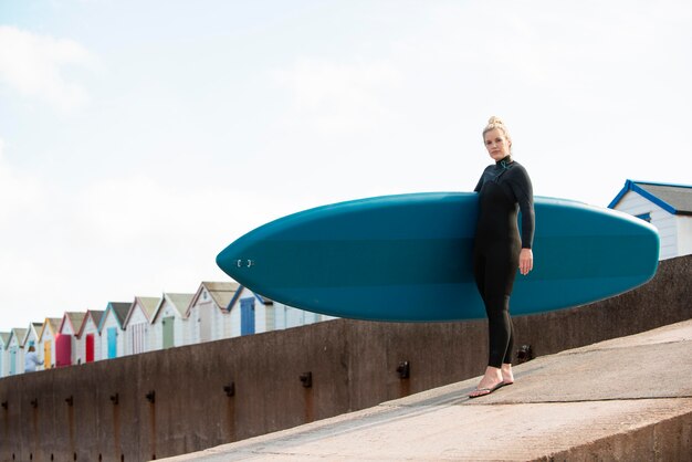 Full shot woman carrying paddleboard