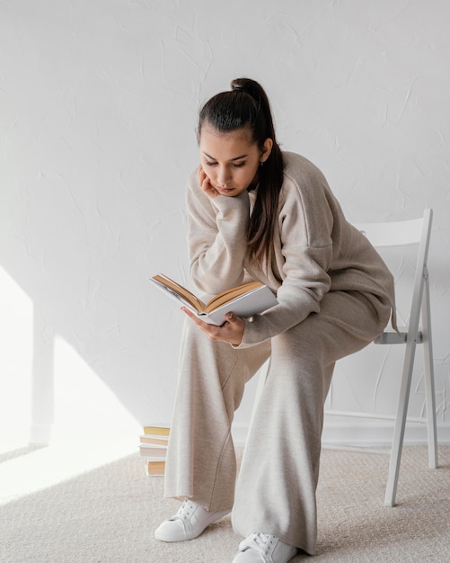 Foto gratuita donna piena del colpo sulla lettura della sedia