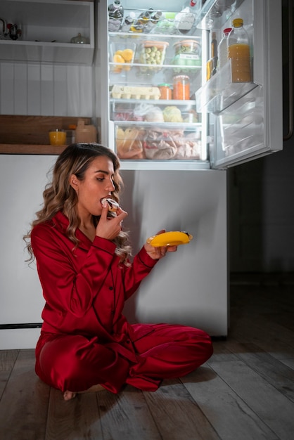 Foto gratuita donna a figura intera che controlla il frigorifero di notte