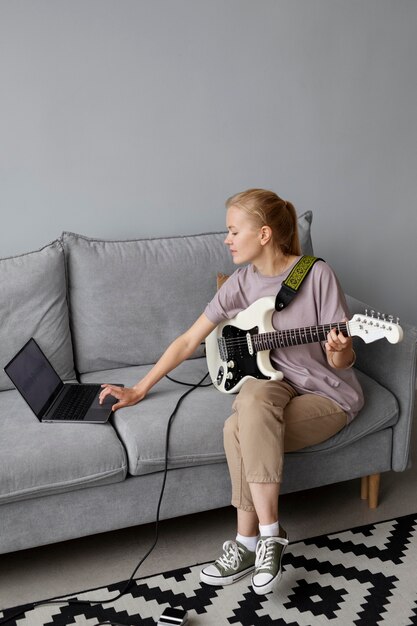 Полный снимок женщины на диване с гитарой