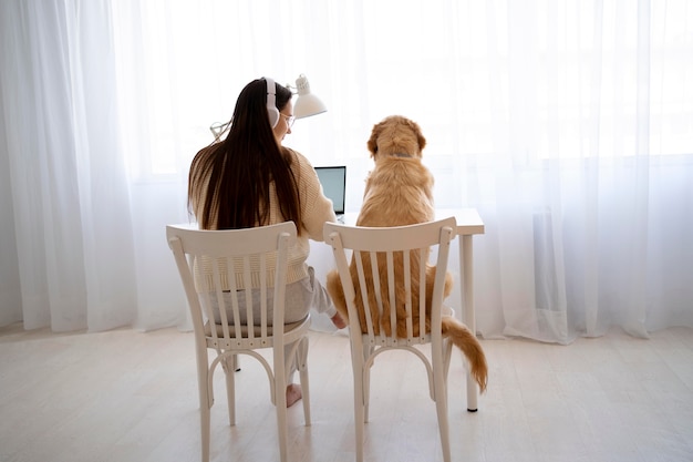 Free photo full shot woman and dog sitting on chairs