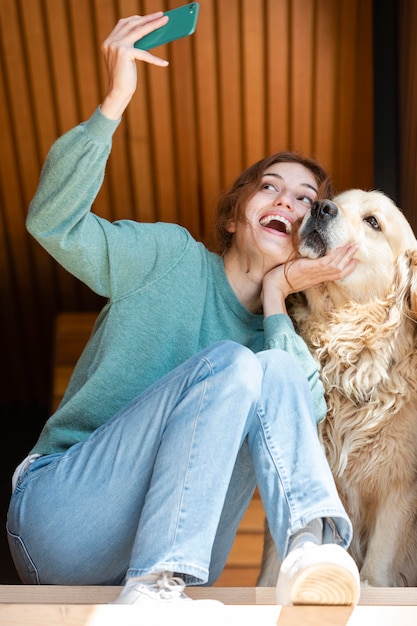 Free photo full shot woman and dog taking selfie