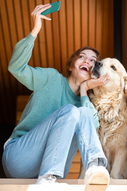 Full shot woman and dog taking selfie