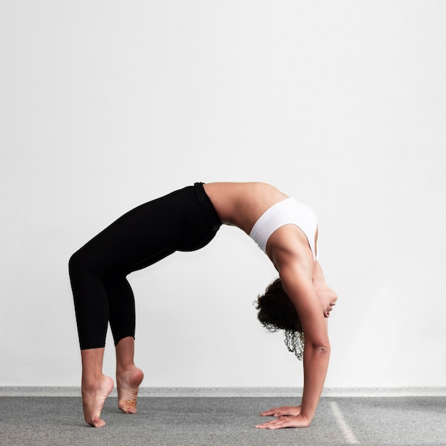 Donna della foto a figura intera che fa un esercizio di ginnastica complesso