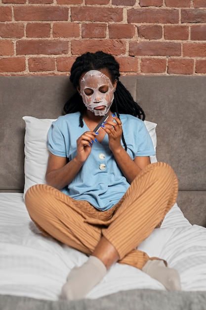 Free photo full shot woman doing her nails in bed