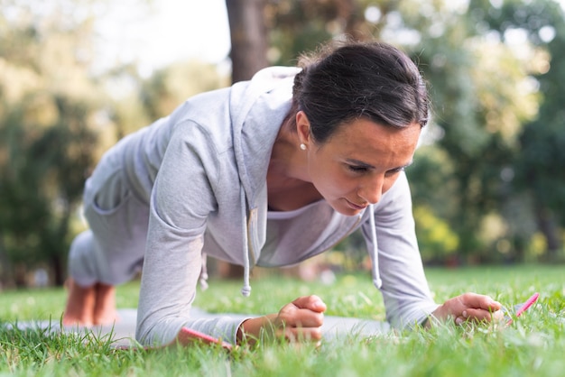 Full shot woman doing planks in nature