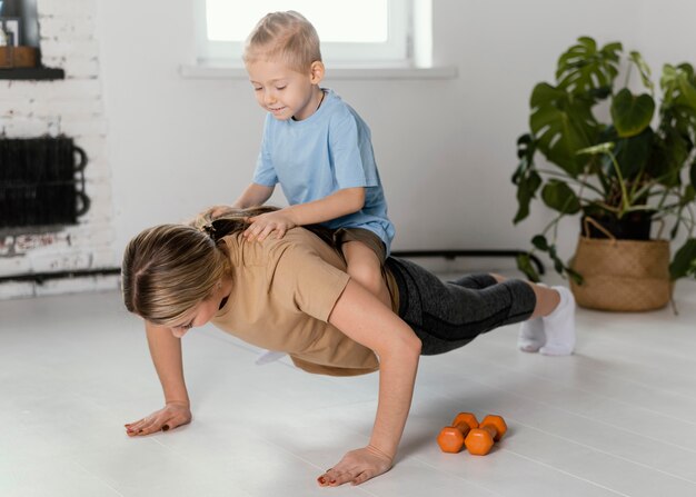 Full shot woman doing pushups with kid