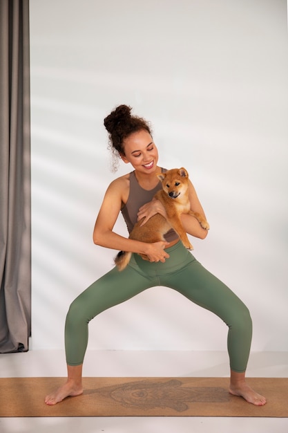 Foto gratuita donna del colpo pieno che fa sport con il cane all'interno