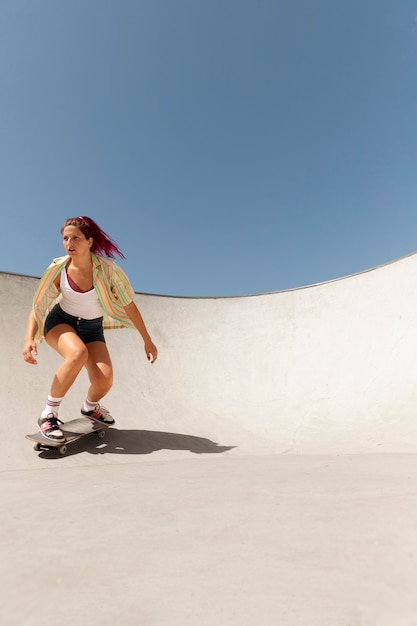 スケートボードでトリックをしているフルショットの女性