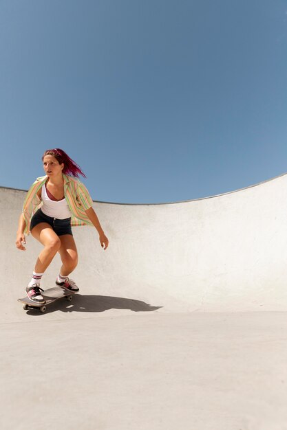 Женщина в полный рост делает трюки на скейтборде