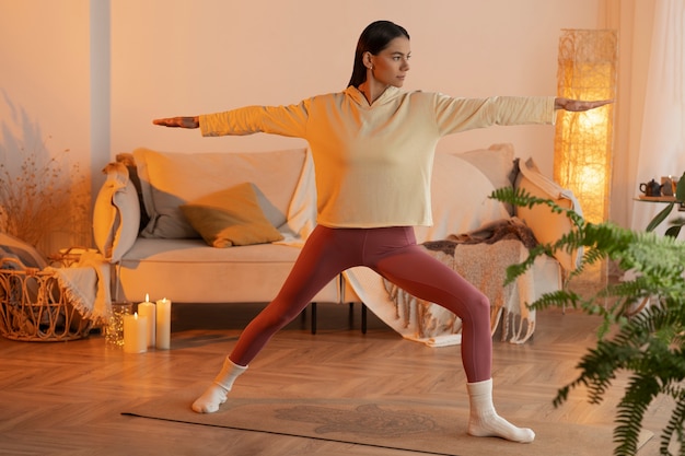 Free photo full shot woman doing yoga indoors