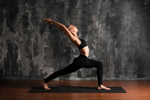 Full shot woman doing yoga on mat