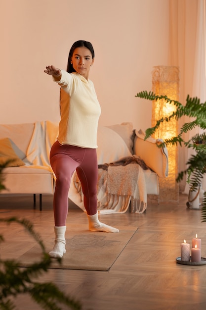 Free photo full shot woman doing yoga on mat