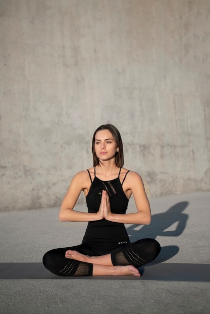 Foto gratuita donna a tutto campo che fa yoga all'aperto