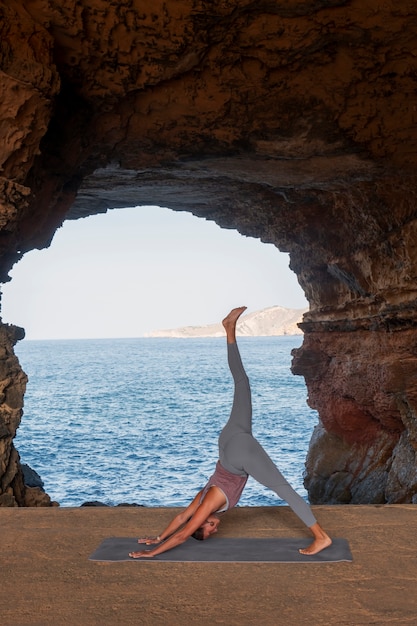 Foto gratuita donna a tutto campo che fa posa yoga in riva al mare