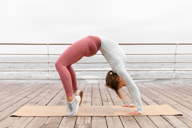 Foto gratuita donna del colpo pieno che fa posa di yoga