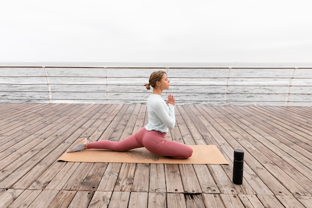 Donna del colpo pieno che fa yoga al mare