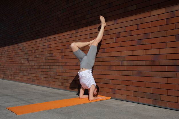 Full shot woman doing yoga with wall